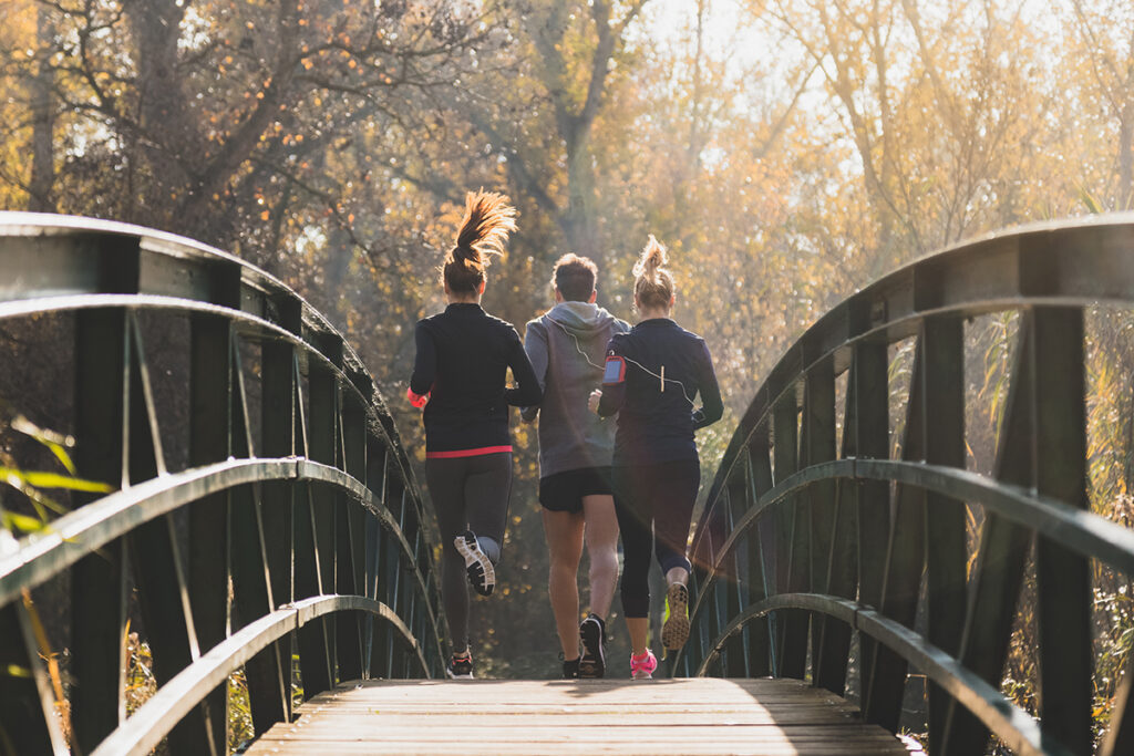 rear-view-healthy-people-running-across-bridge